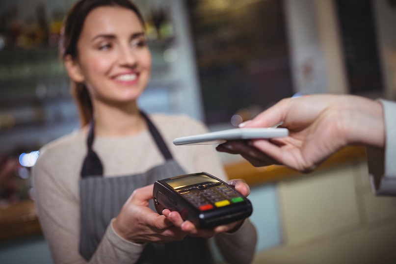 Woman paying bill through smartphone using NFC technology in cafe